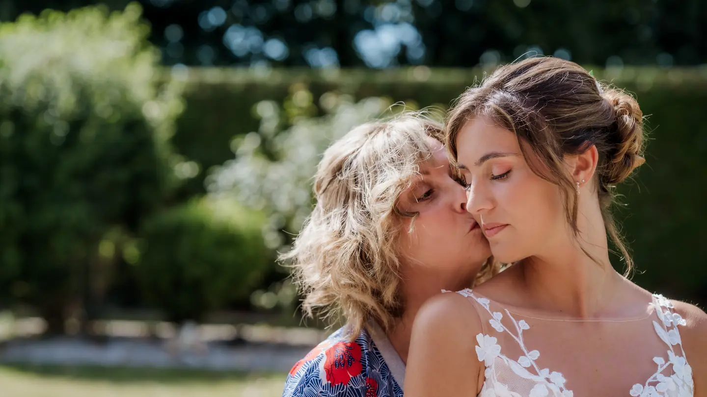 La mère de la mariée l'embrasse sur la joue