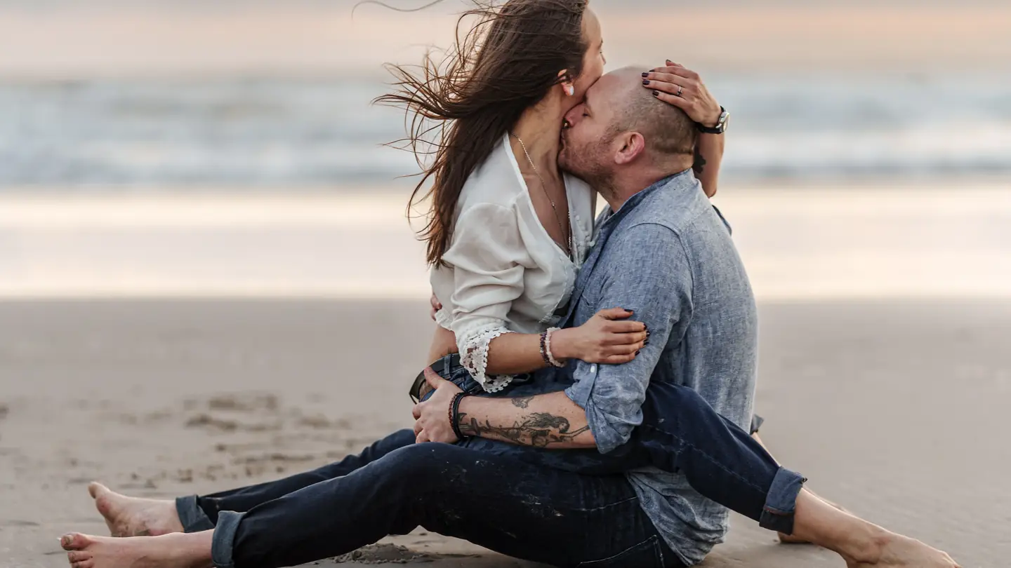 Cyndel et François enlacés sur le sable, cheveux au vent