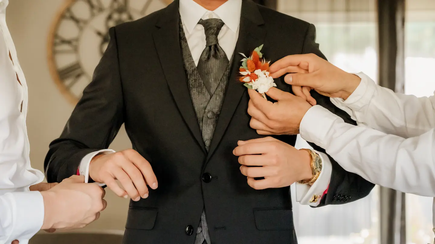 On épingle la boutonnière du marié pendant les préparatifs