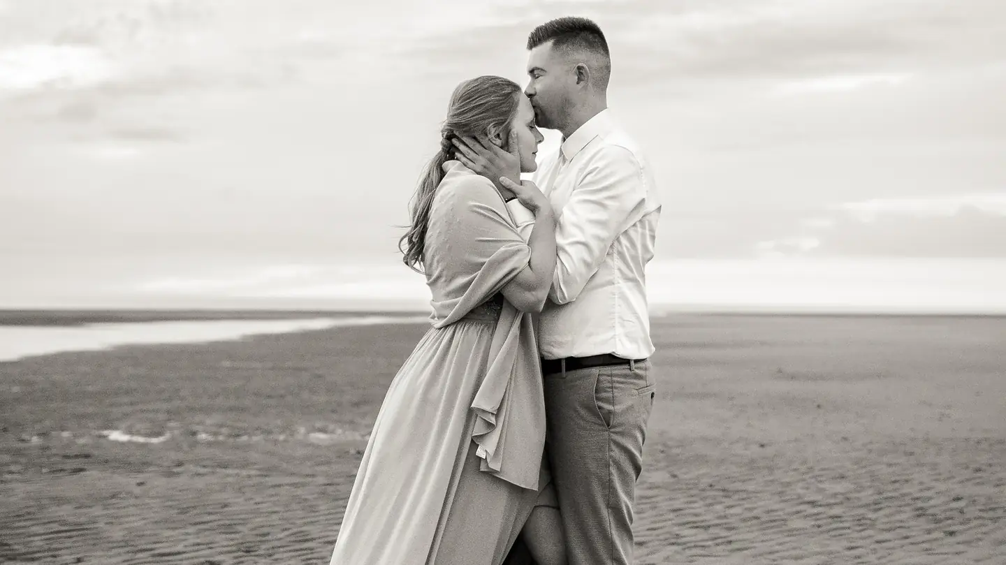 Blandine et Cédric enlacés sur le sable, en noir et blanc