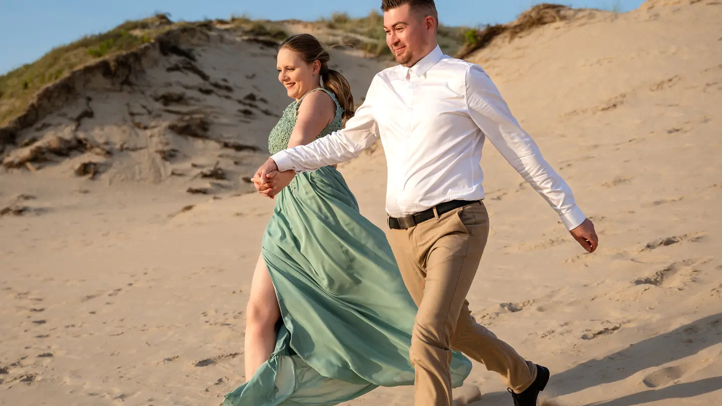 Blandine et Cédric courent dans les dunes sous le ciel bleu