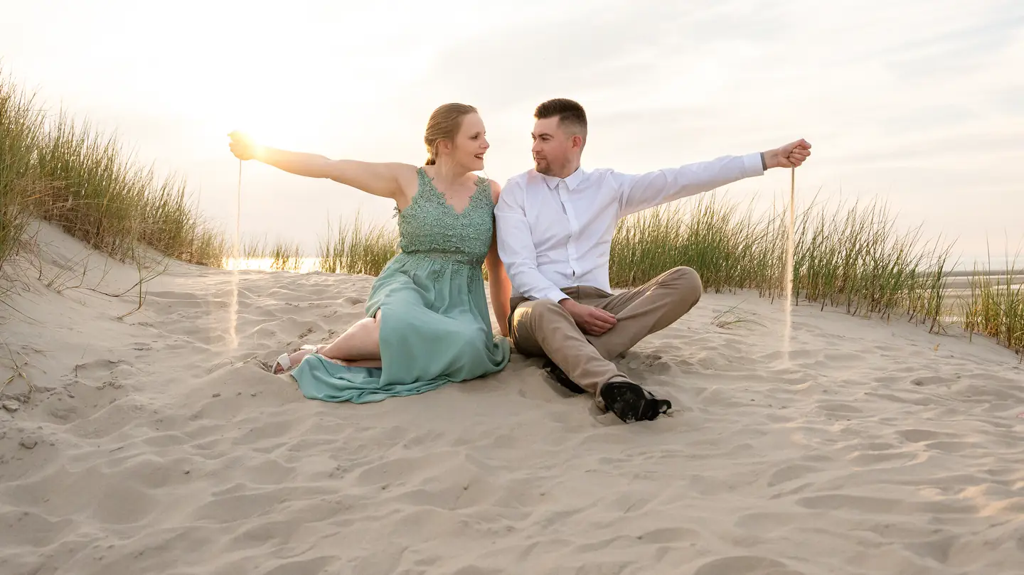 Blandine et Cédric assis dans les dunes, bras ouverts