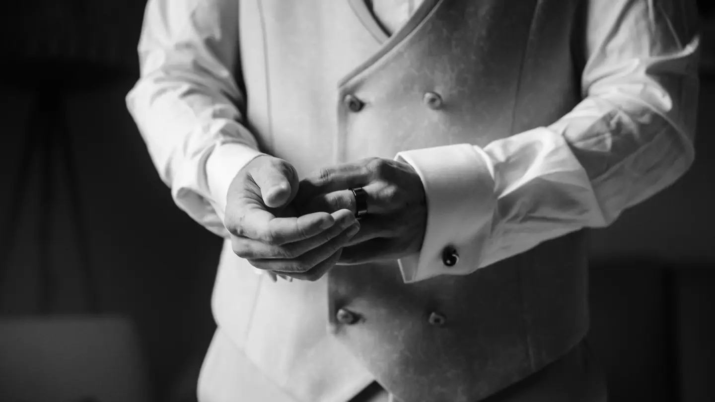 Les mains du marié en gilet, en noir et blanc