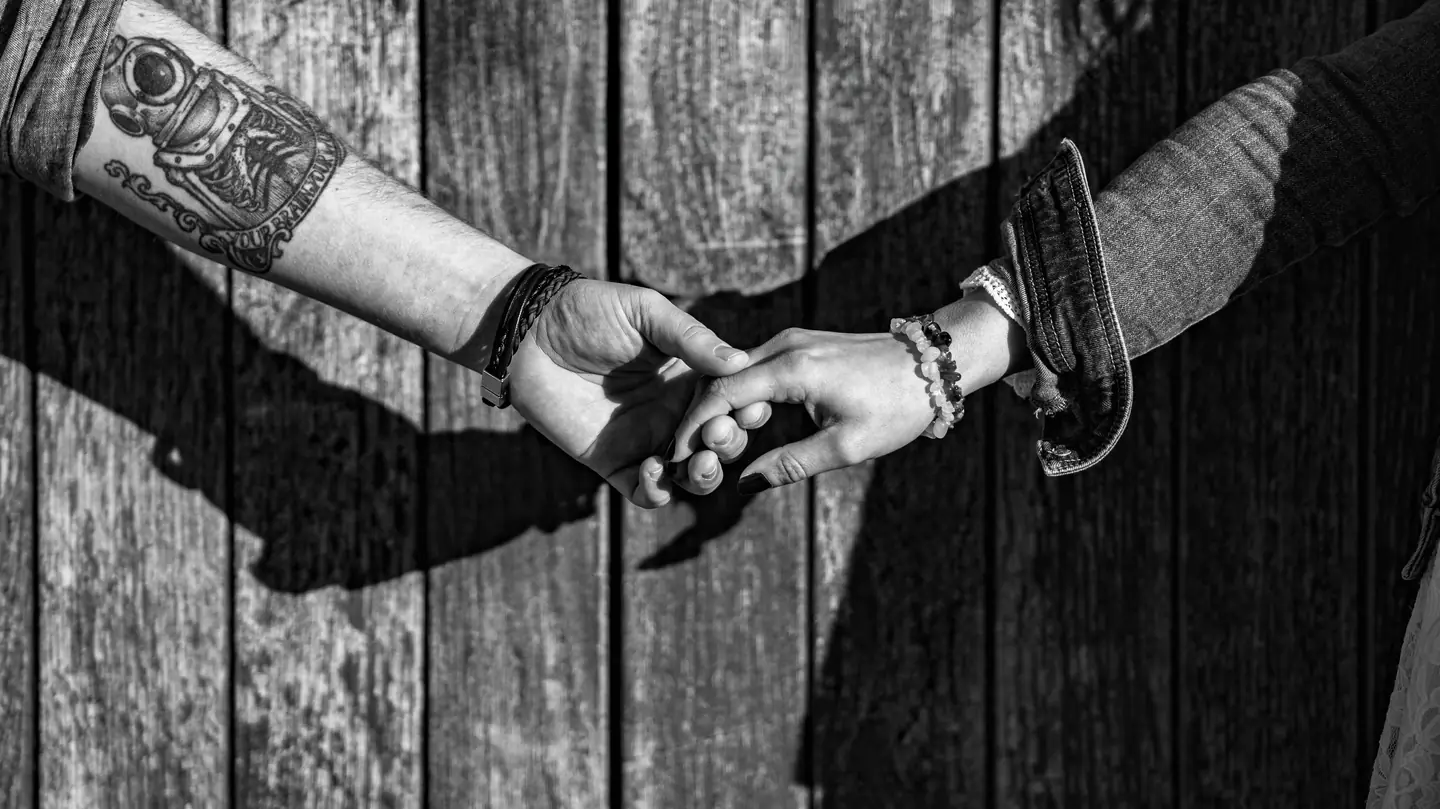 Mains entrelacées et tatouées, en noir et blanc