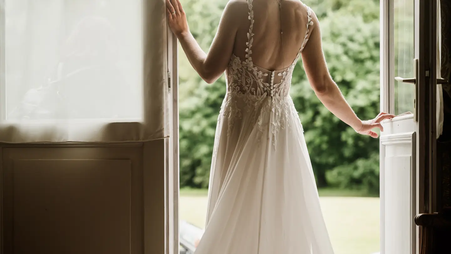La mariée de dos à la fenêtre, avant le first look
