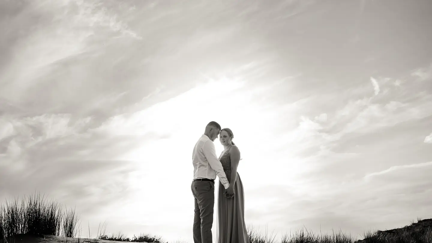 Silhouettes du couple en contre-jour sur la plage, en noir et blanc