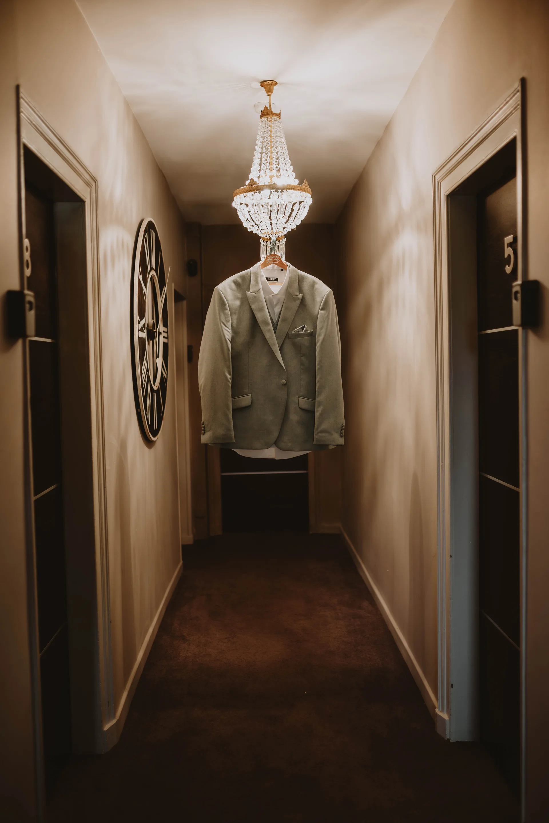 Détails mariage — costume suspendu au lustre